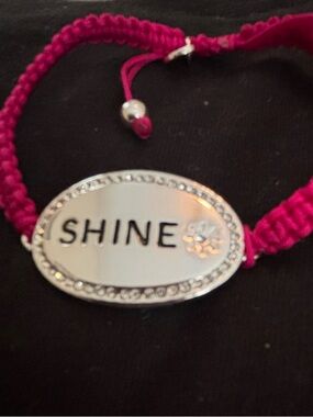 Fuchsia corded bracelet with silver bar that says Shine. Has crystal accents
